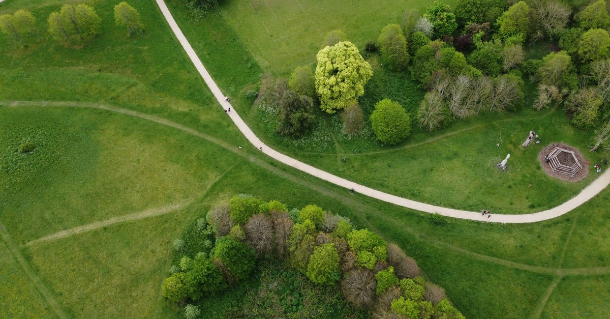 A captivating aerial view of a lush green park with winding paths and dense tree coverage in Houghton Regis, England.