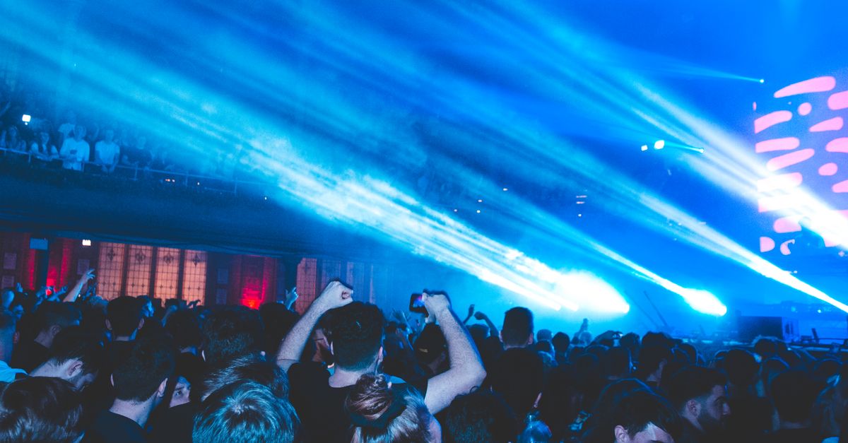 Vibrant nightclub scene with crowd enjoying music and blue laser lights.