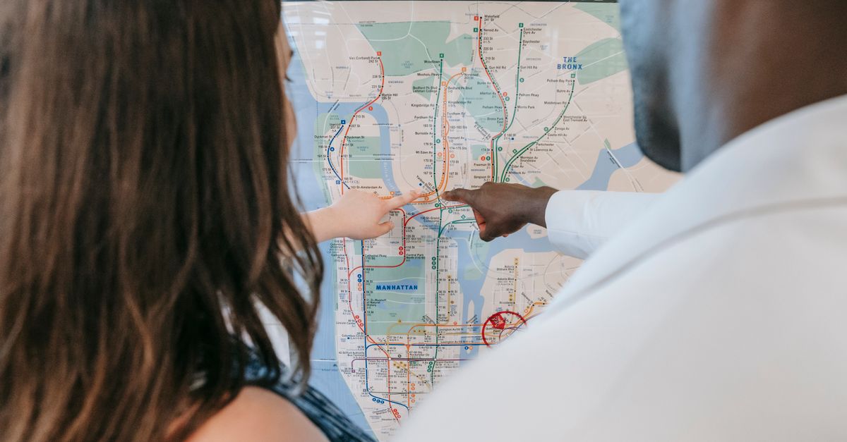 A couple examines a subway map, planning their route at a station.