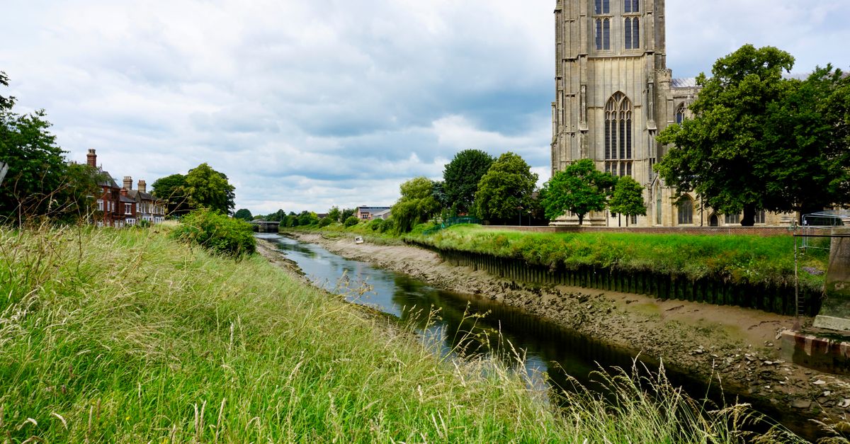 A scenic view of St Botolph's Church beside a river in Boston, England, United Kingdom.