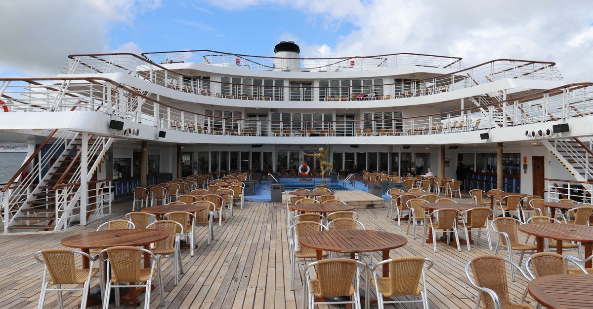 Empty cruise ship deck with tables and chairs, ideal for leisure travel.