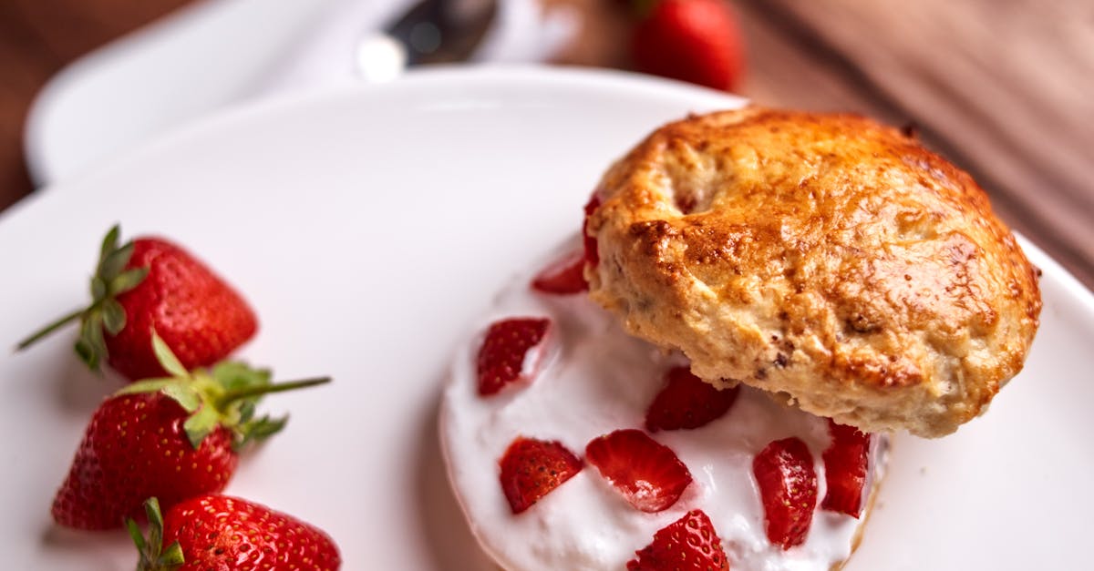 Close-up of a strawberry shortcake with whipped cream and fresh strawberries on a white plate.