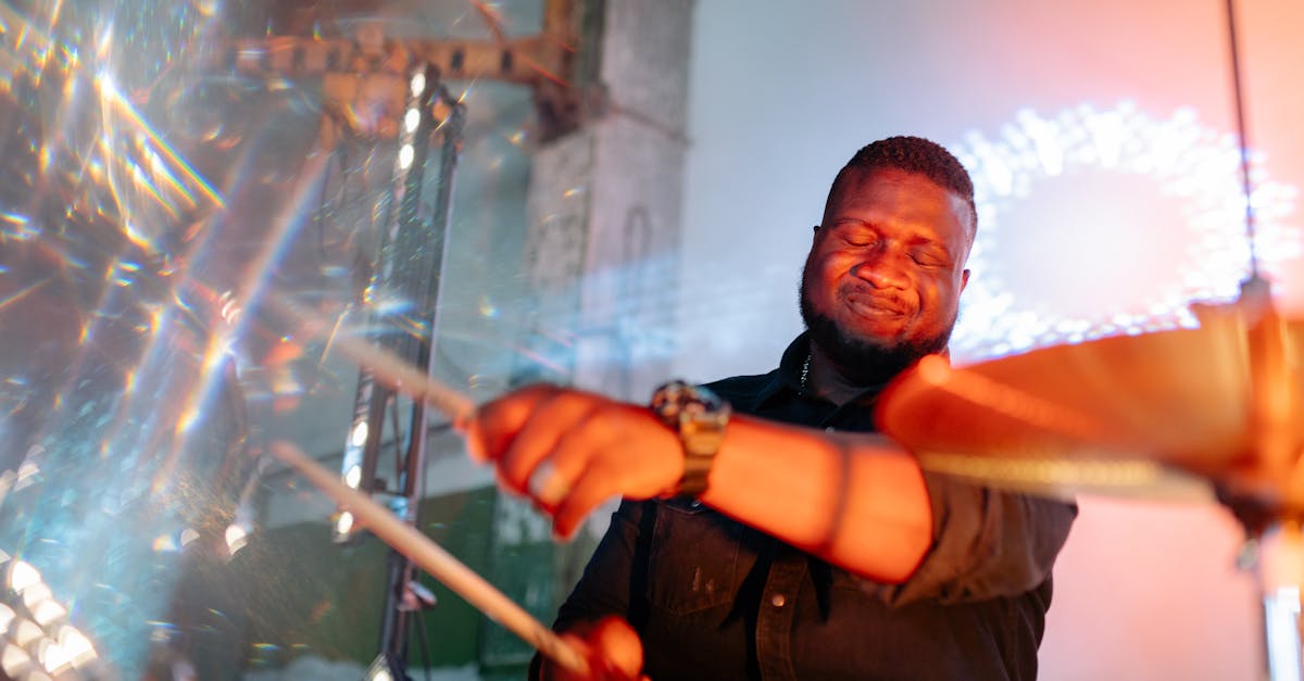 Drummer passionately playing during a lively music performance with vibrant lights.