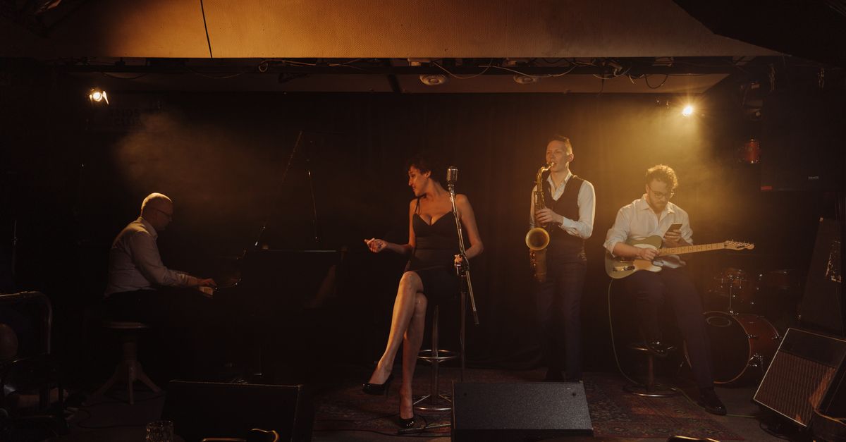 A jazz band performing with a female singer and musicians playing piano, saxophone, and guitar on stage.