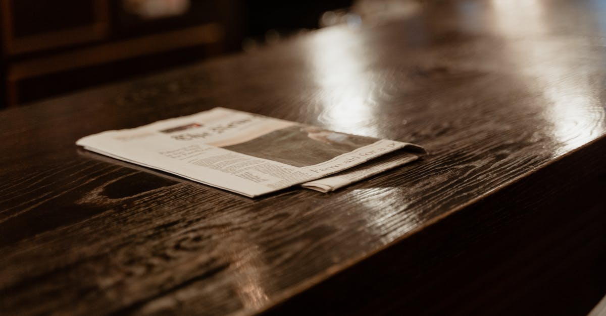 A still life shot of a newspaper resting on a polished wooden table in a cozy indoor setting.
